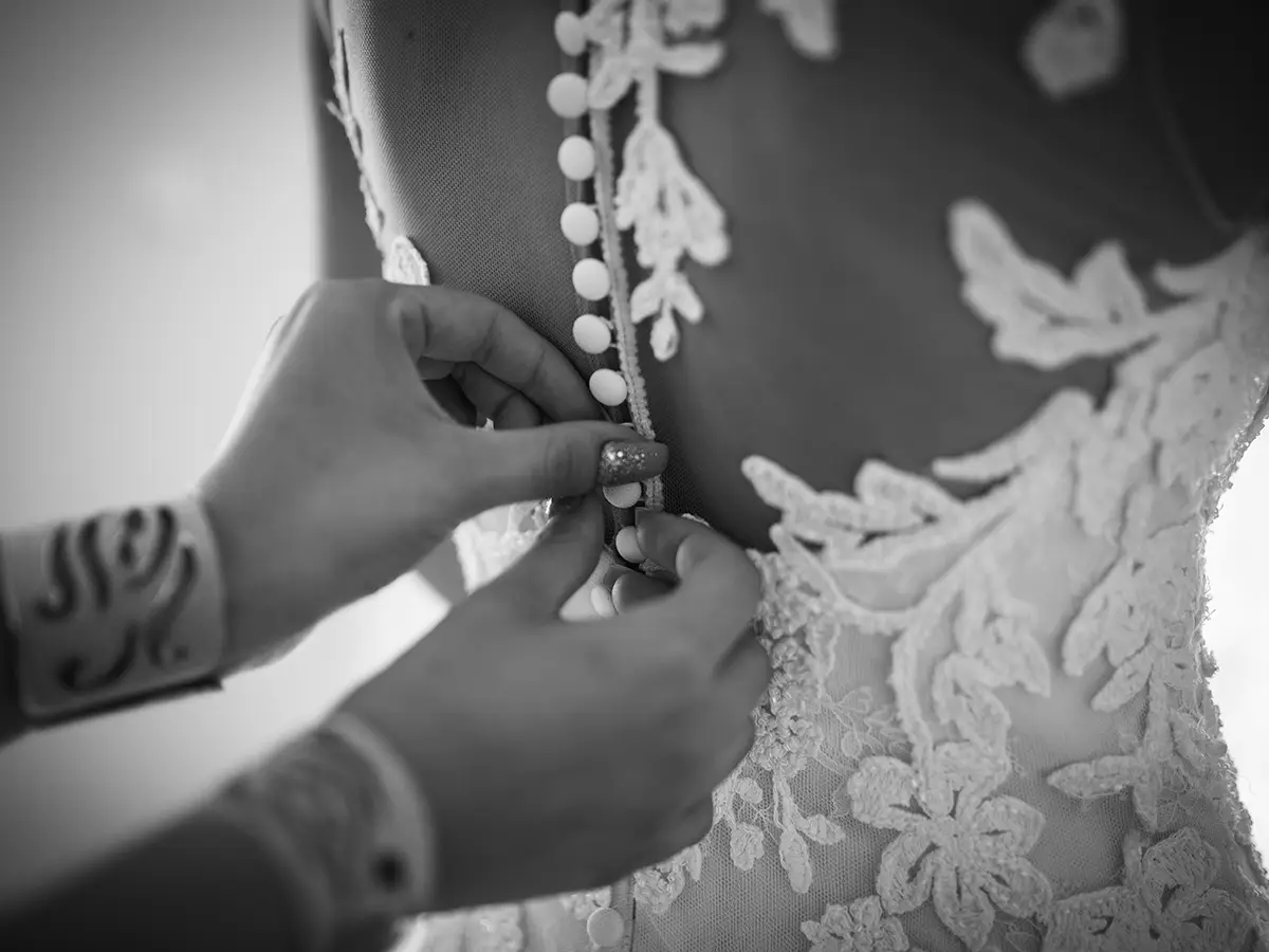 Brautkleid wird zugeknöpft, Schwarzweißaufnahme